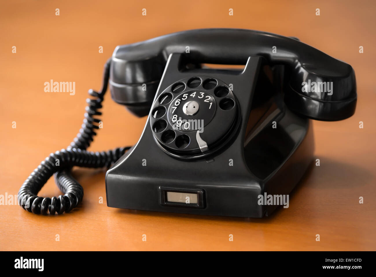 Old fashioned retro rotary dial phone on wooden desk Stock Photo
