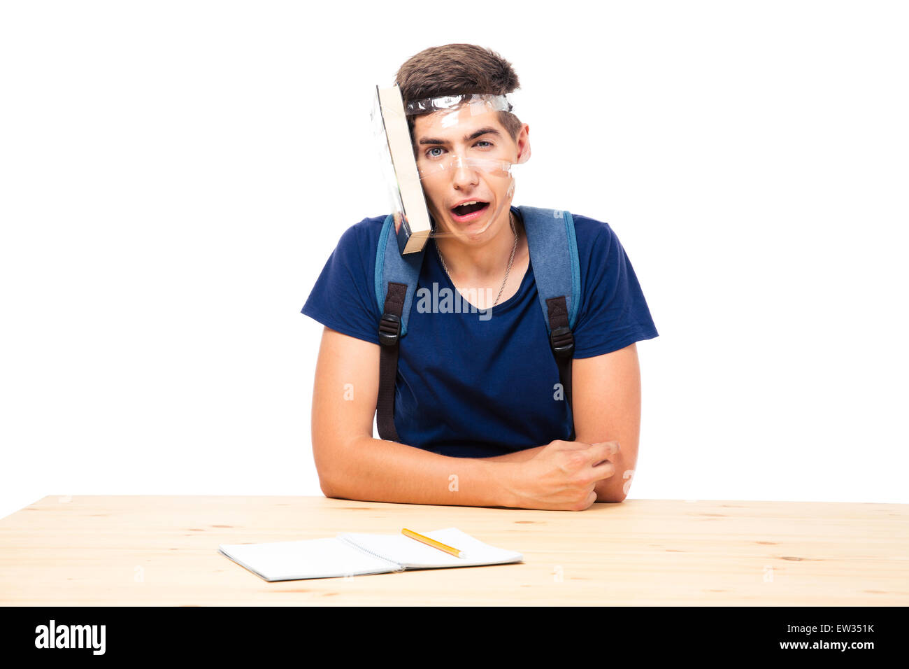 Male student with book strapped to his head sitting at the table isolated on a white background Stock Photo