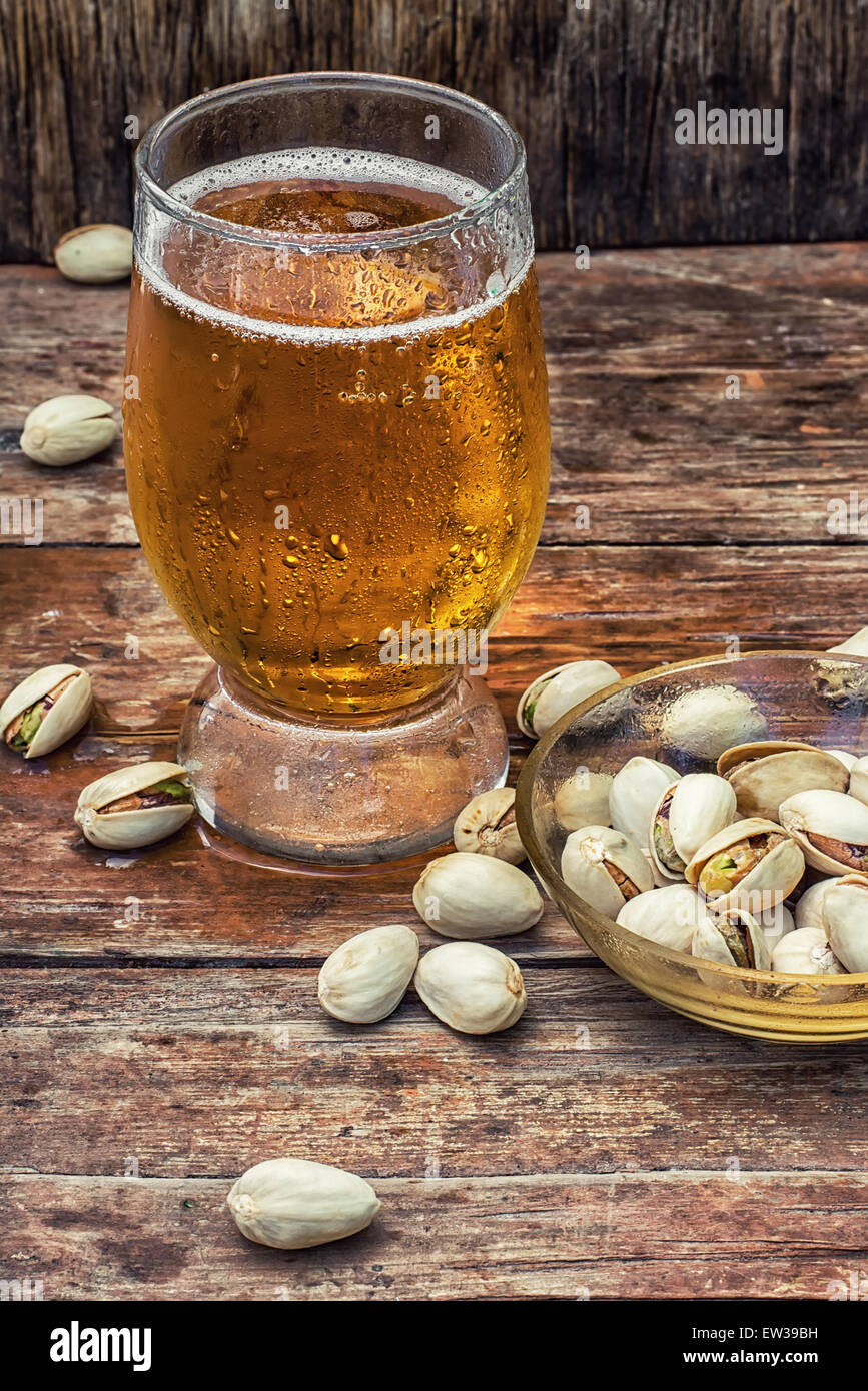 beer light beer on wooden table with saucer of salted pistachios.Photo
