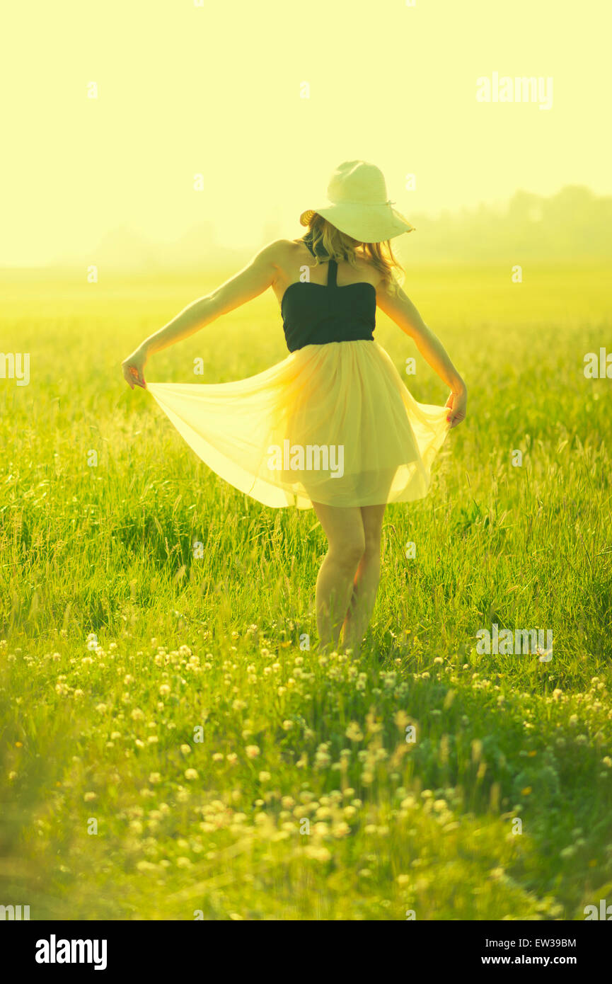 Summer fashion portrait of young woman in dress and sunhat in a field Stock Photo