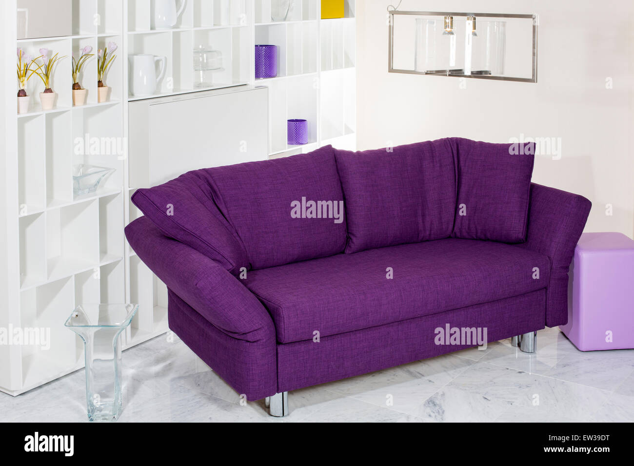 purple couch in front of white wall unit Stock Photo