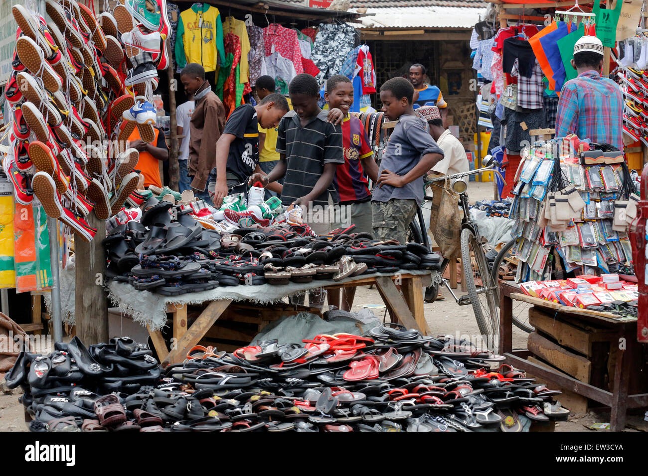 Young boys looking for shoes at an outdoor shoe shop on Zansibar island, Tansania, Africa Stock Photo