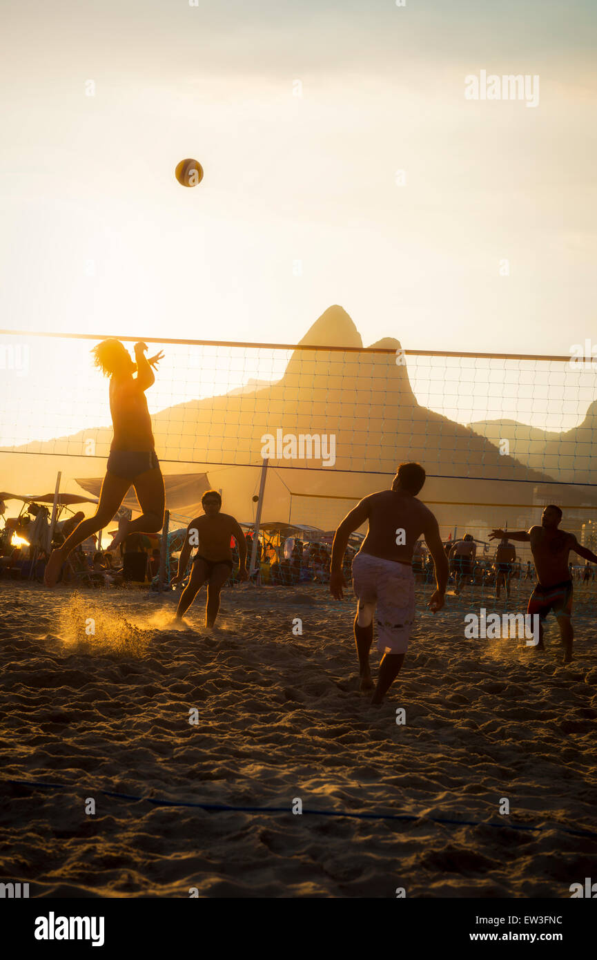 RIO DE JANEIRO, BRAZIL - FEBRUARY 01, 2014: Young carioca Brazilians play a game of beach volleyball against the sunset, Stock Photo