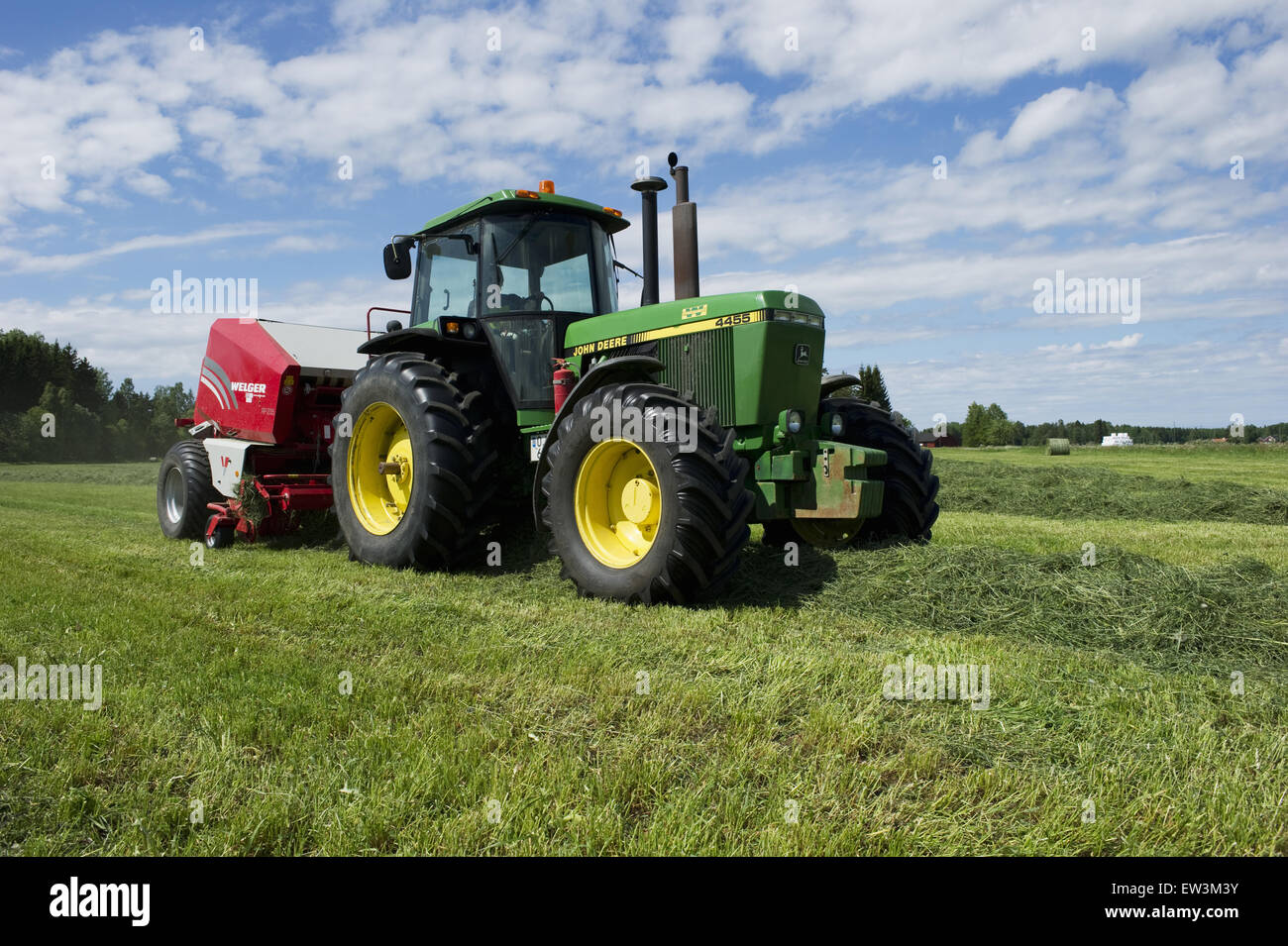 John Deere 4455 tractor and Welger baler, baling silage crop, Sweden, June Stock Photo