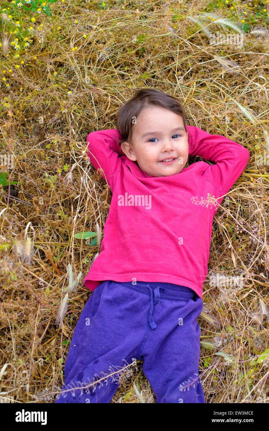 Portrait of a little girl smiling as she lies in the grass Stock Photo ...