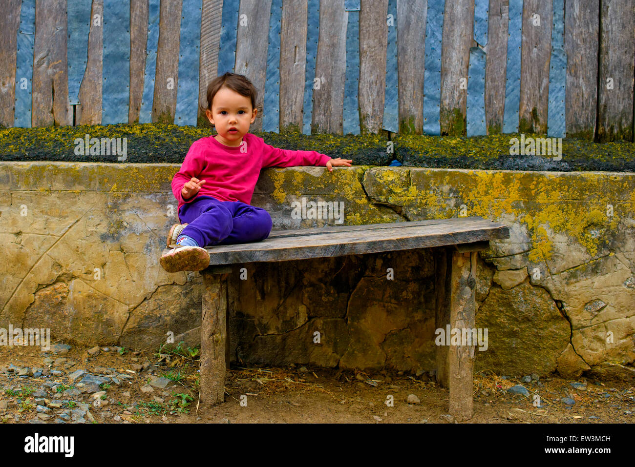 Two years old  girl sitting on rustic bench Stock Photo