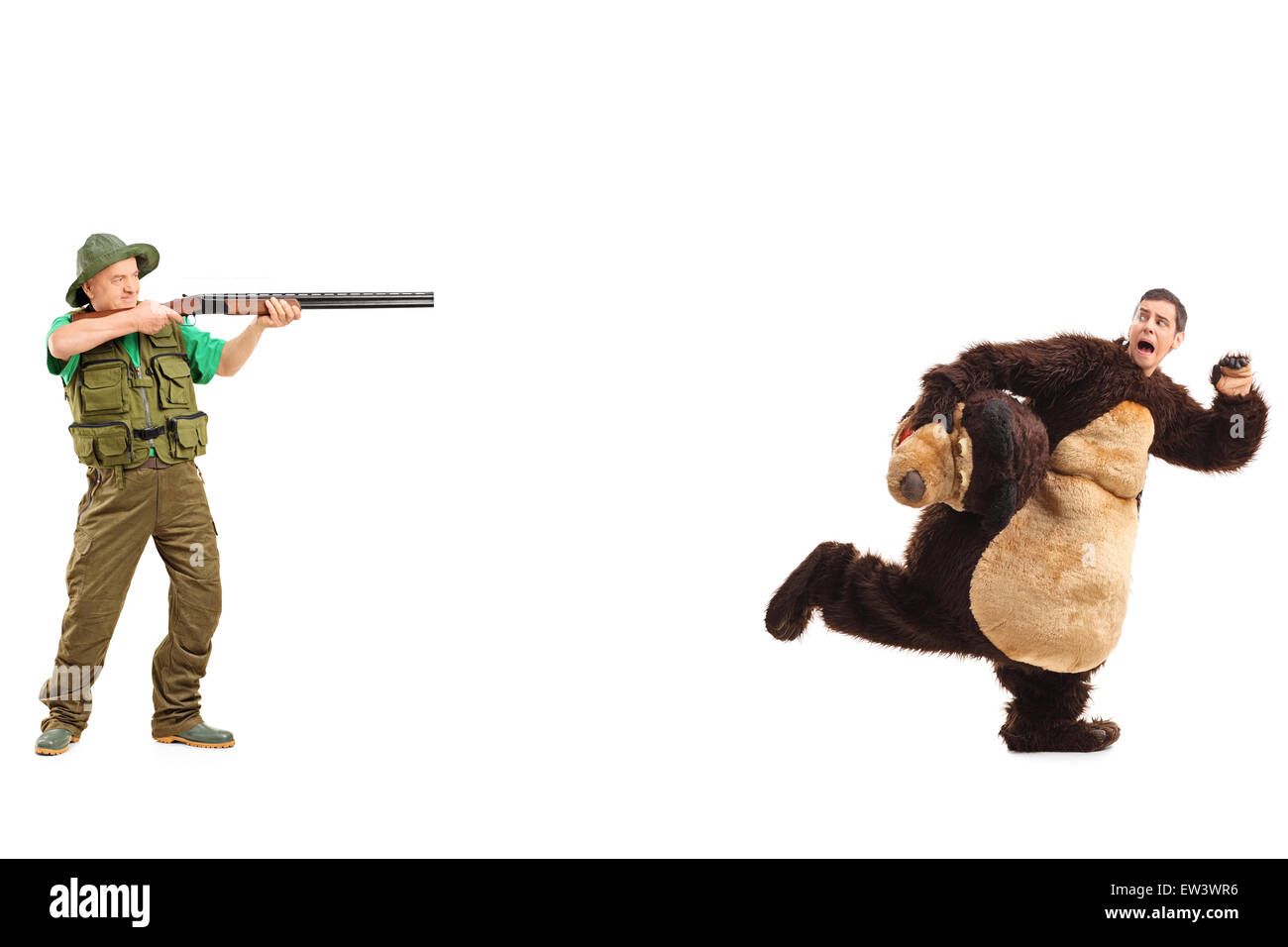 Full length portrait of a mature hunter aiming a rifle towards a man in a bear costume Stock Photo