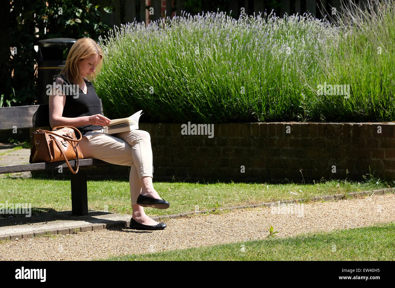 young woman reading a book in urban park Stock Photo