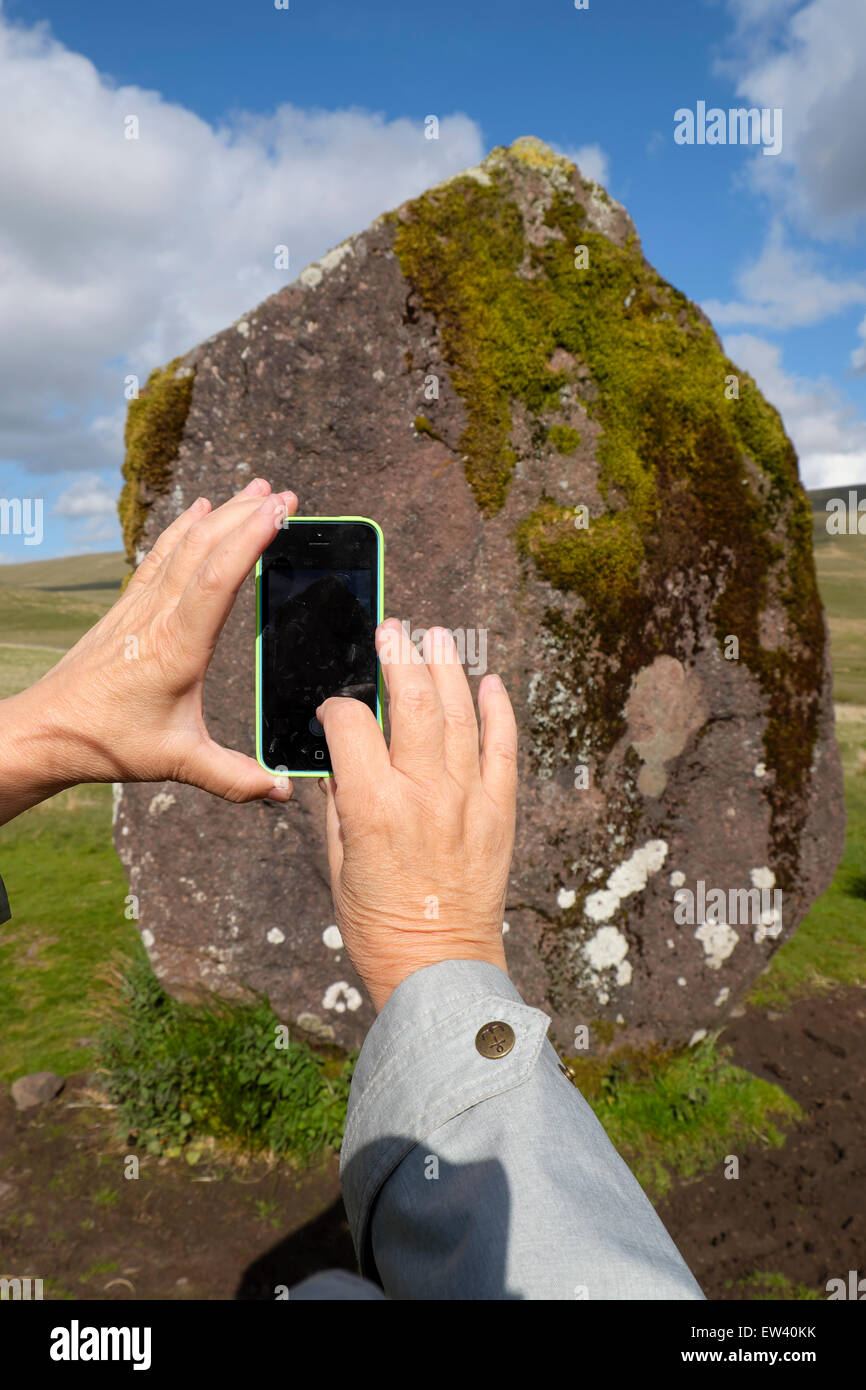 A woman with photographs the standing stone Maen Llia in the Brecon Beacons National Park, Powys Wales, UK  KATHY DEWITT Stock Photo