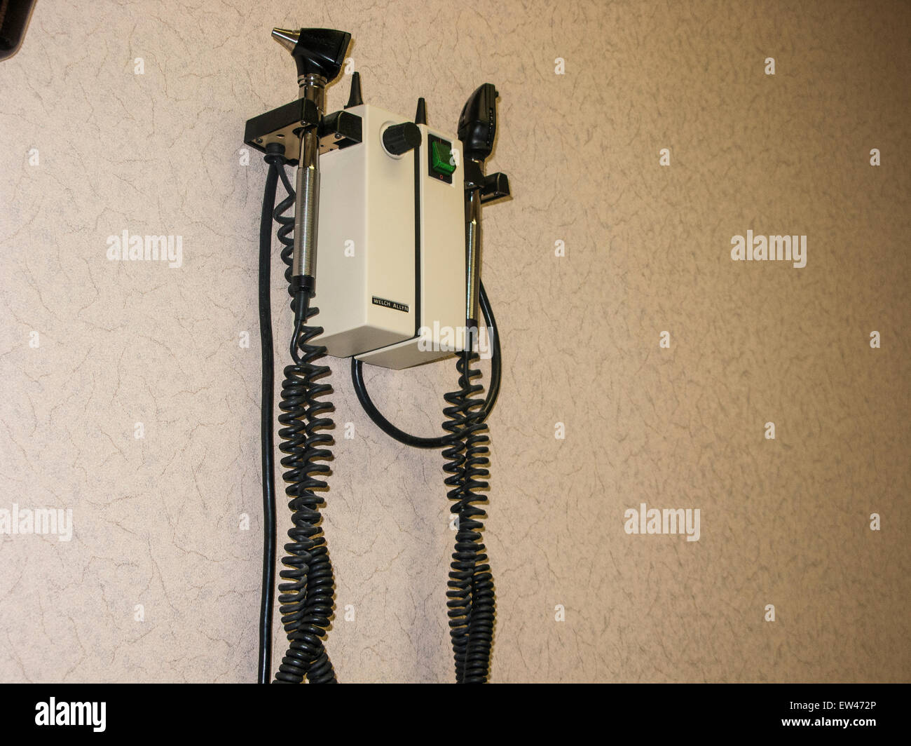 A Welch Allyn otoscope and Opthalmoscope combo hanging on a wall in a doctor's examination room. Stock Photo