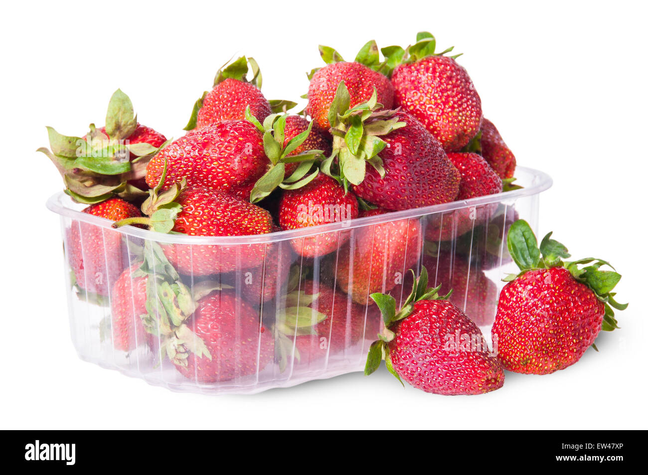 Freshly strawberries in a plastic tray and two near rotated isolated on