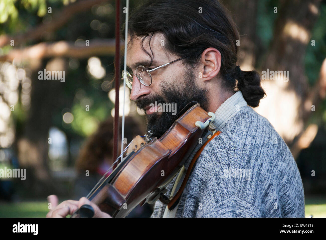 Violinist playing in the park. blurred background. man with glasses. Stock Photo