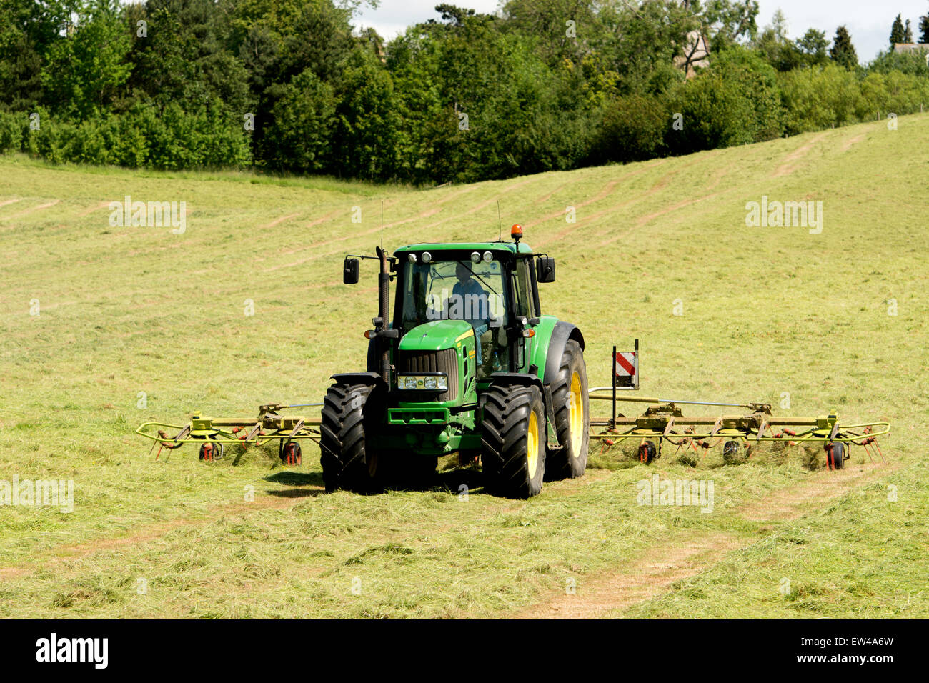 A John Deere tractor turning hay, Northamptonshire, England, UK Stock Photo