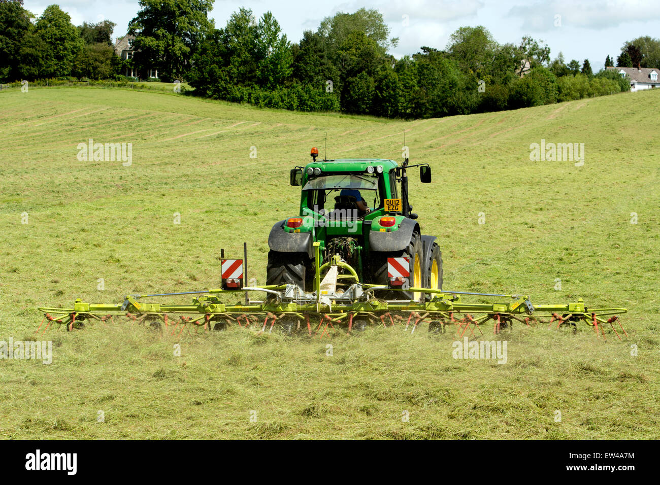 A John Deere tractor turning hay, Northamptonshire, England, UK Stock Photo