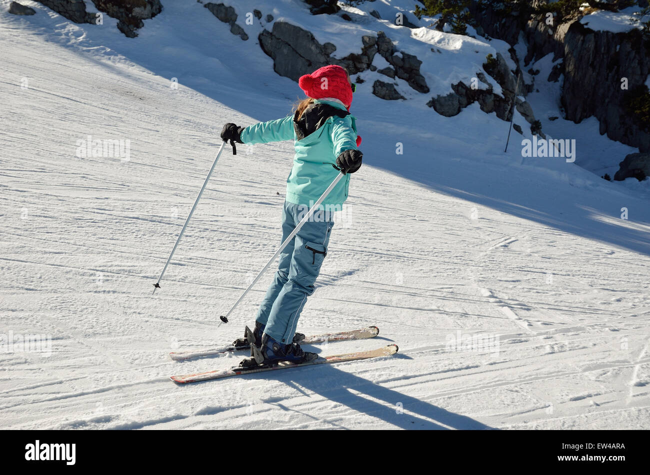 A skier-girl is sliding down on the ski run of compacted snow. Stock Photo