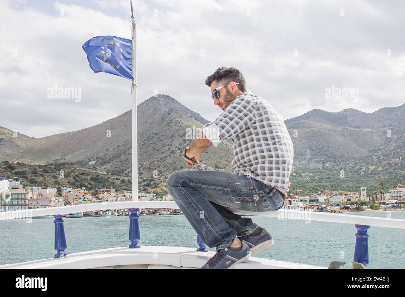 A Greek Captain of a tourist boat checks the time in front of a EU flag. Stock Photo