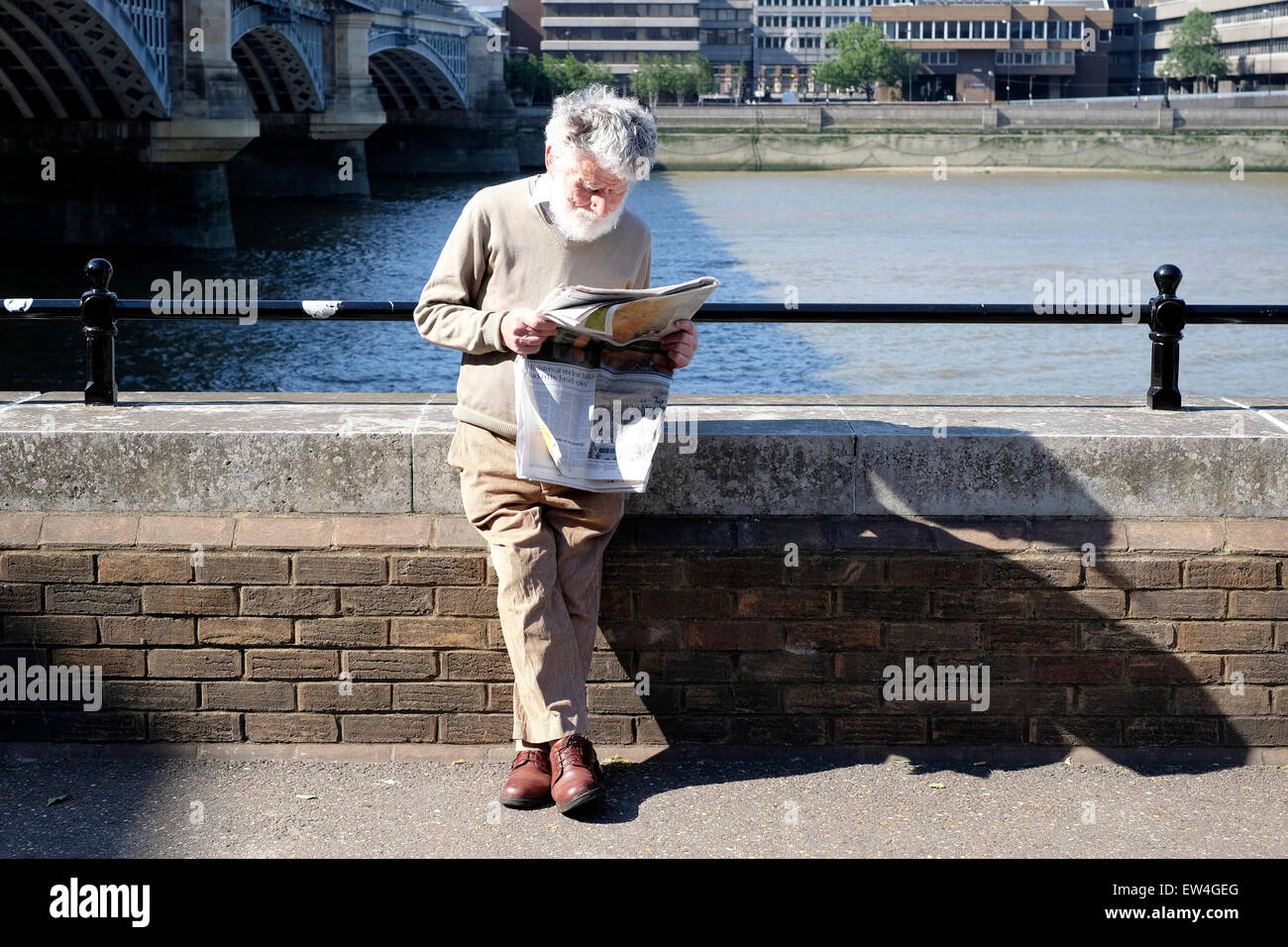 A senior citizen reading a newspaper on the South Bank, London Stock Photo