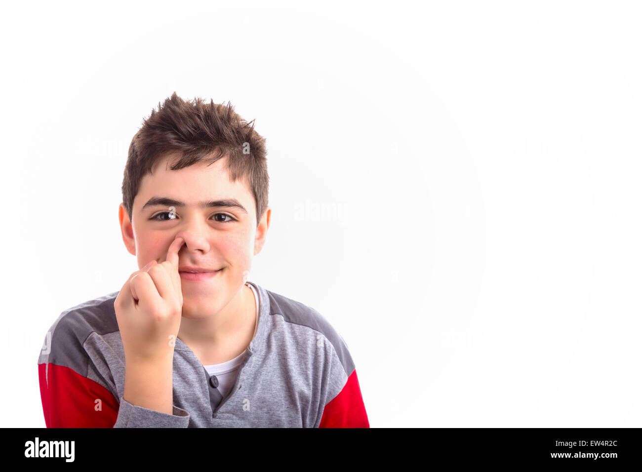 Caucasian boy in red and grey pajamas child picks his nose painting a quizzical smile Stock Photo