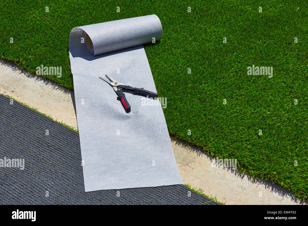 Artificial grass turf installation in garden with tools and joint roll