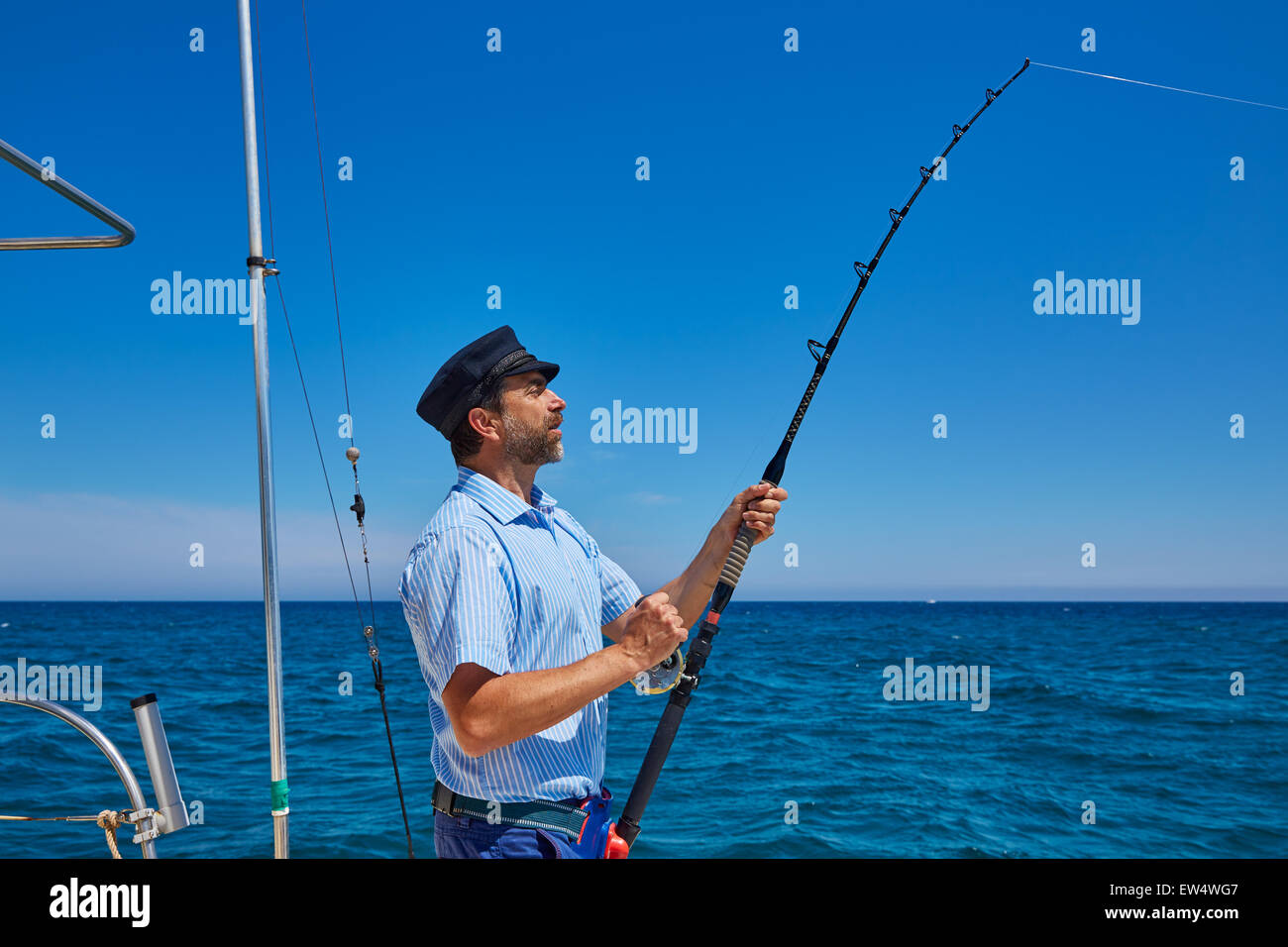 Beard sailor man fishing rod trolling in saltwater in a boat