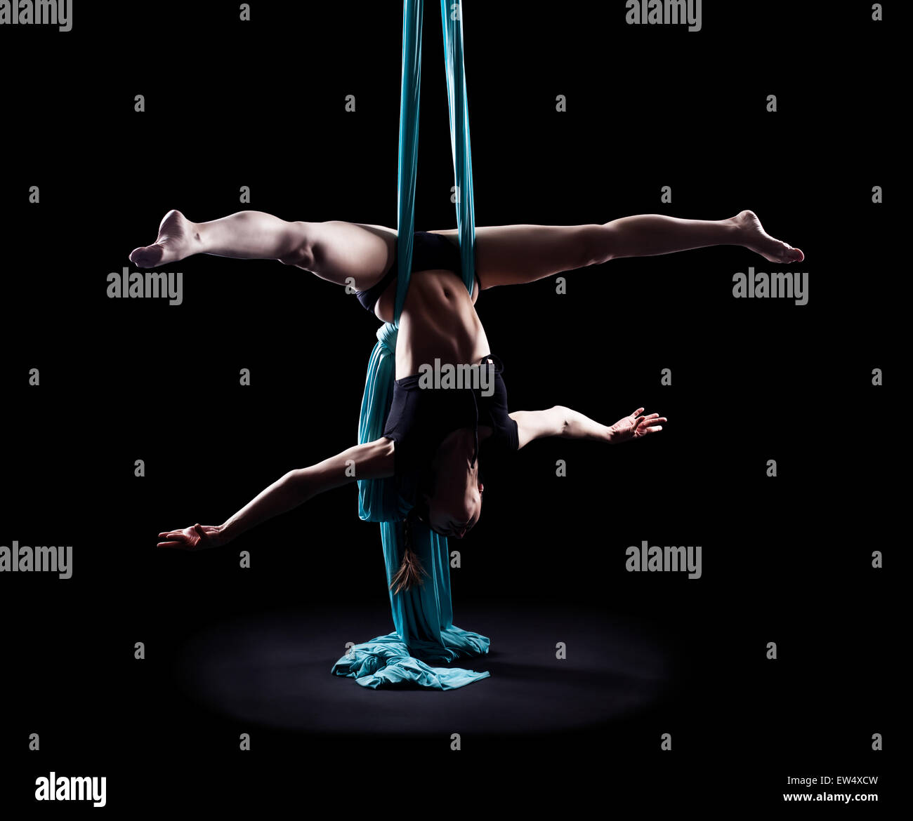 Young woman gymnast with blue gymnastic aerial silks isolated on black Stock Photo
