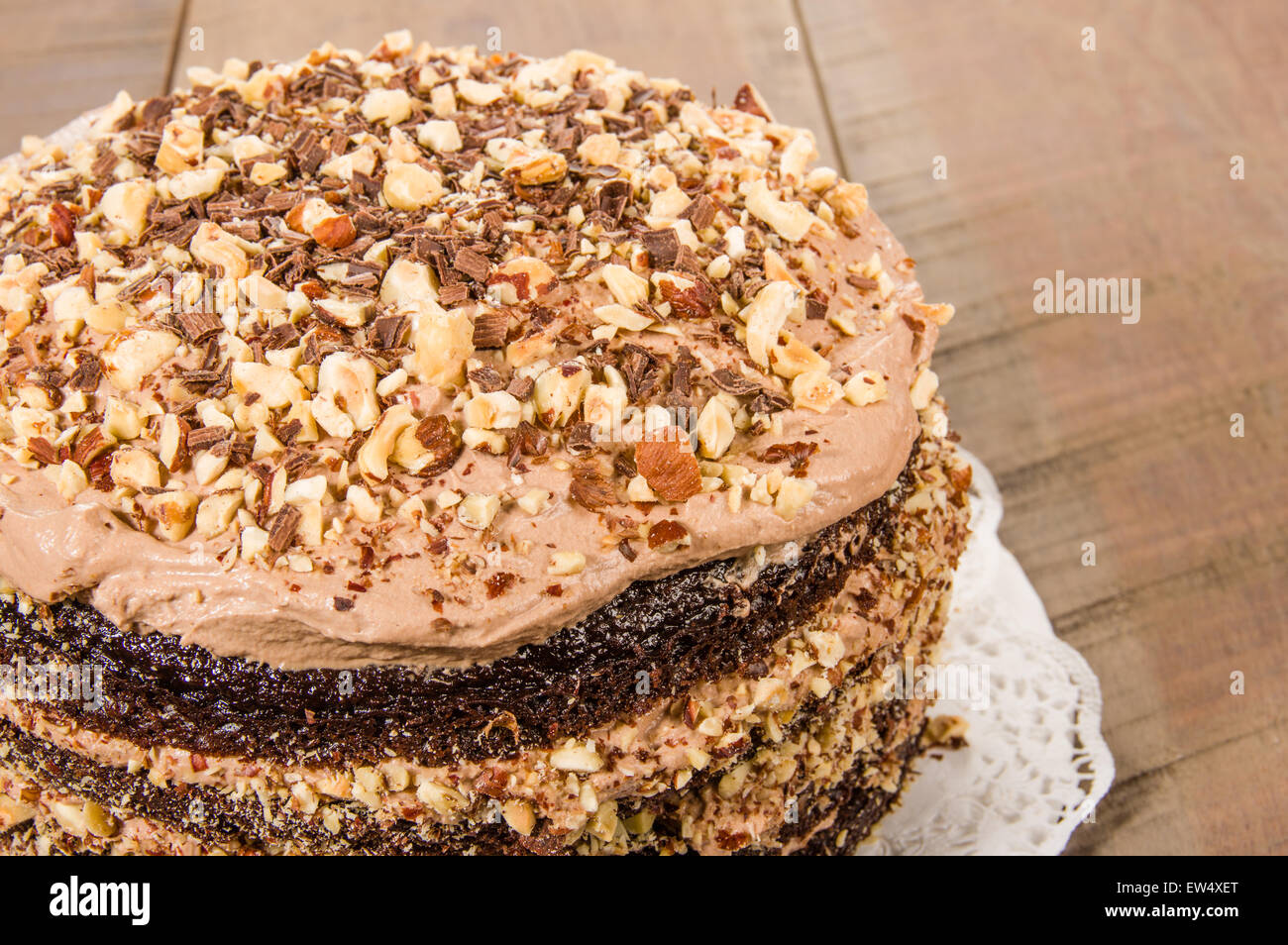 Fresh chocolate cake with icing or frosting and hazelnut topping Stock Photo