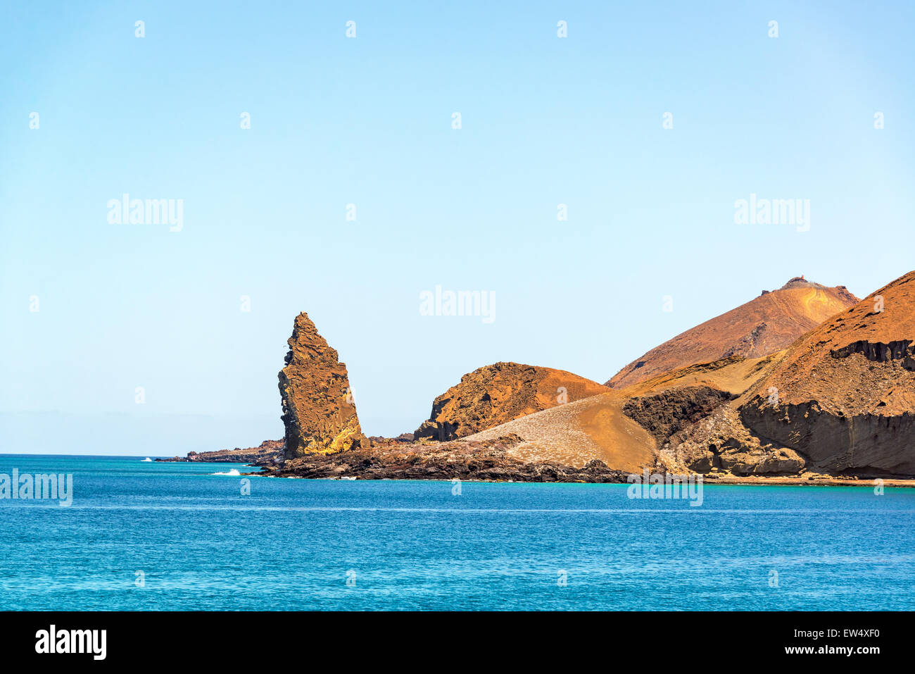 Pinnacle Rock with the ocean and hills on Bartolome Island in the Galapagos Islands in Ecuador Stock Photo