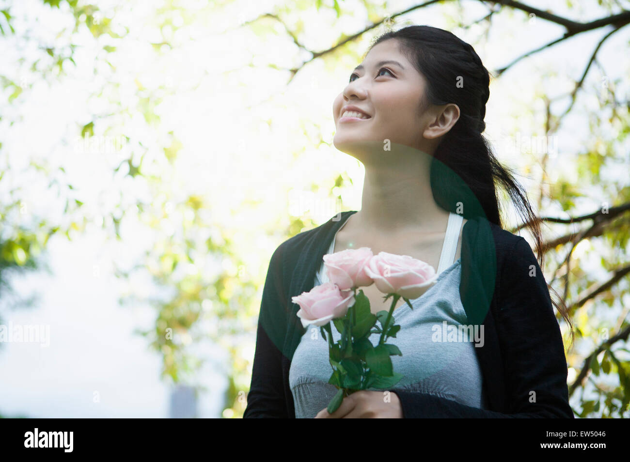 Young woman holding flowers and looking up with smile Stock Photo - Alamy