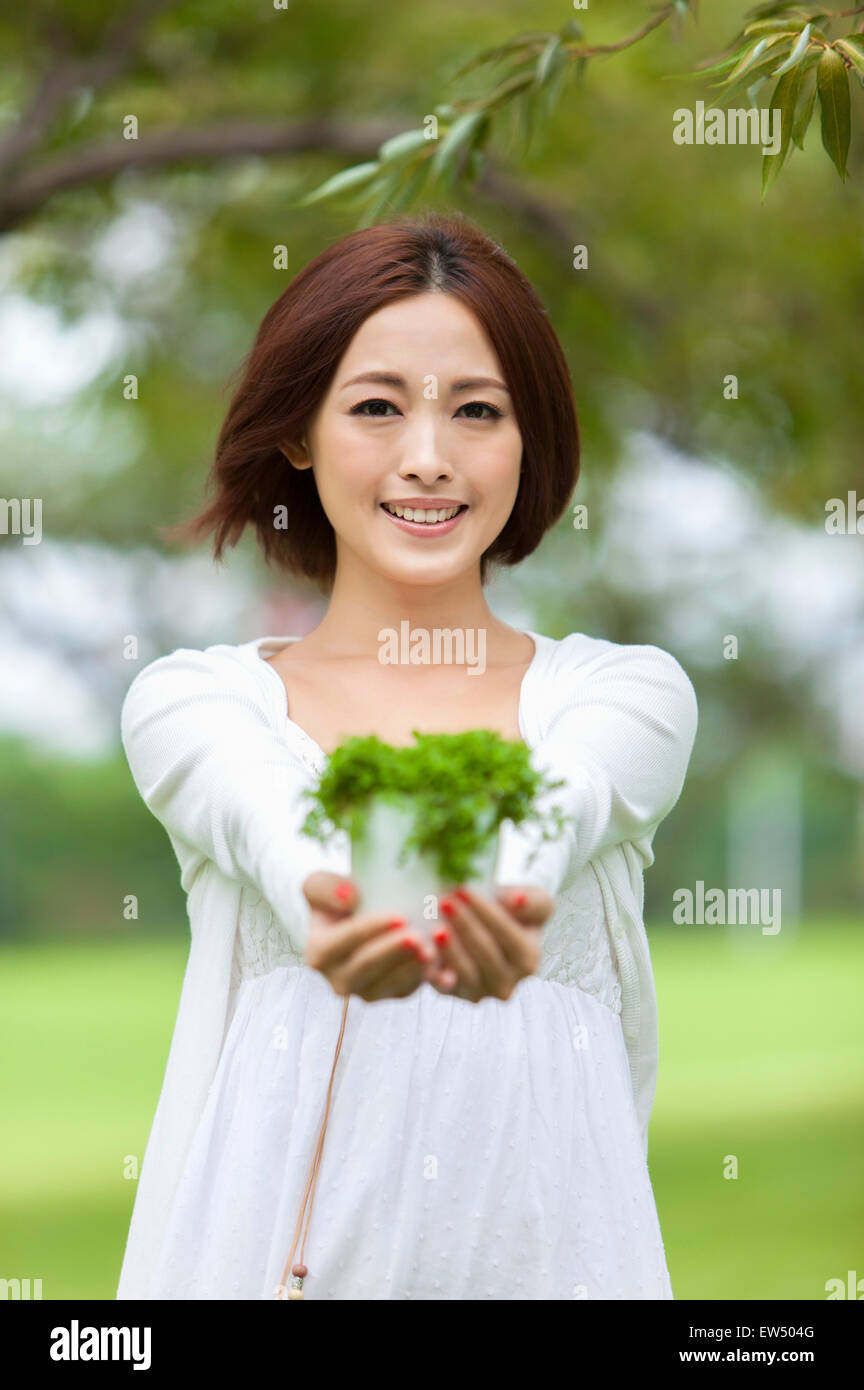 Young woman holding plant and smiling at the camera Stock Photo - Alamy