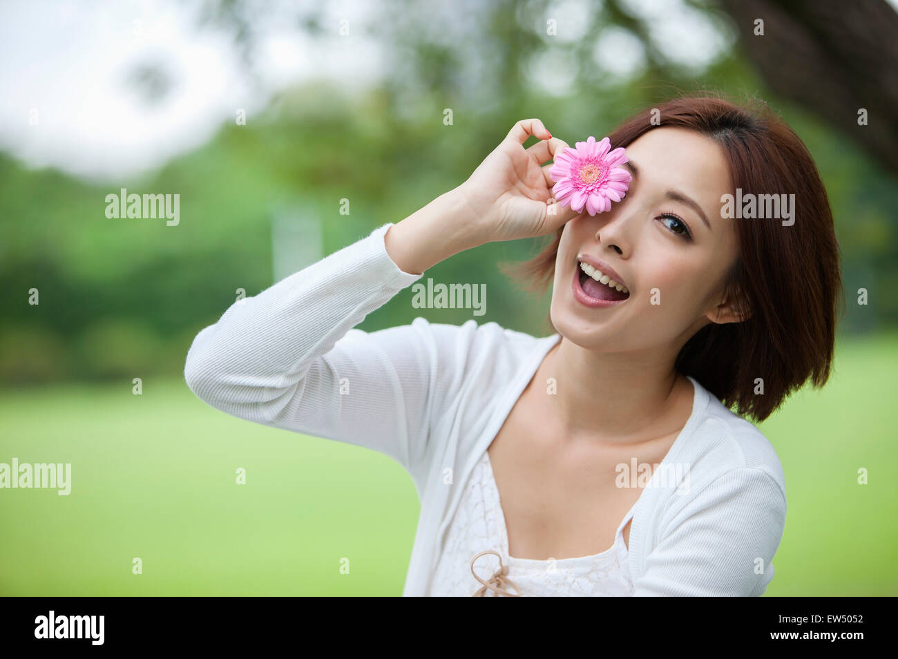 Young woman smiling at the camera with one flower Stock Photo