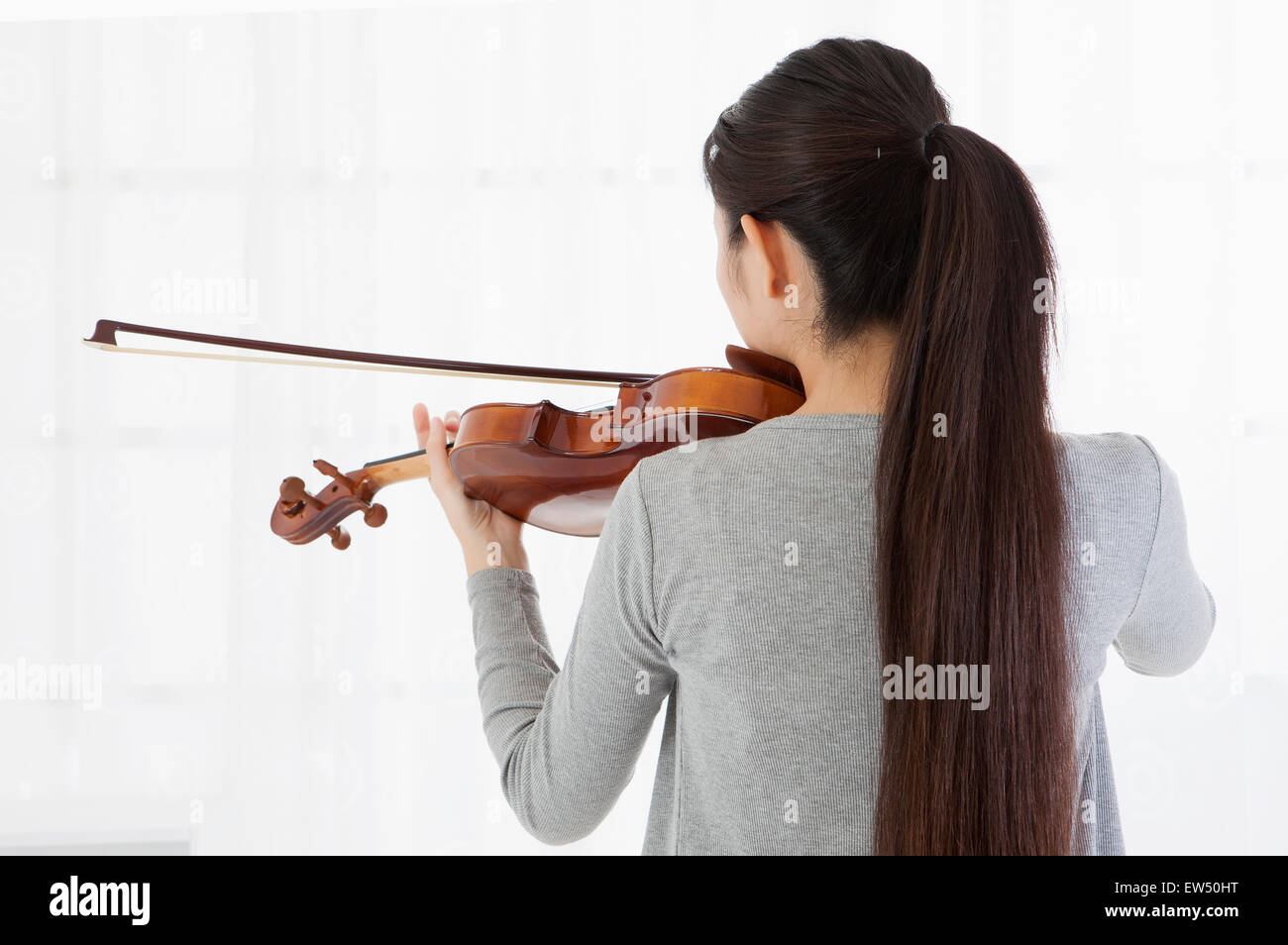 Young woman playing violin with rear view Stock Photo