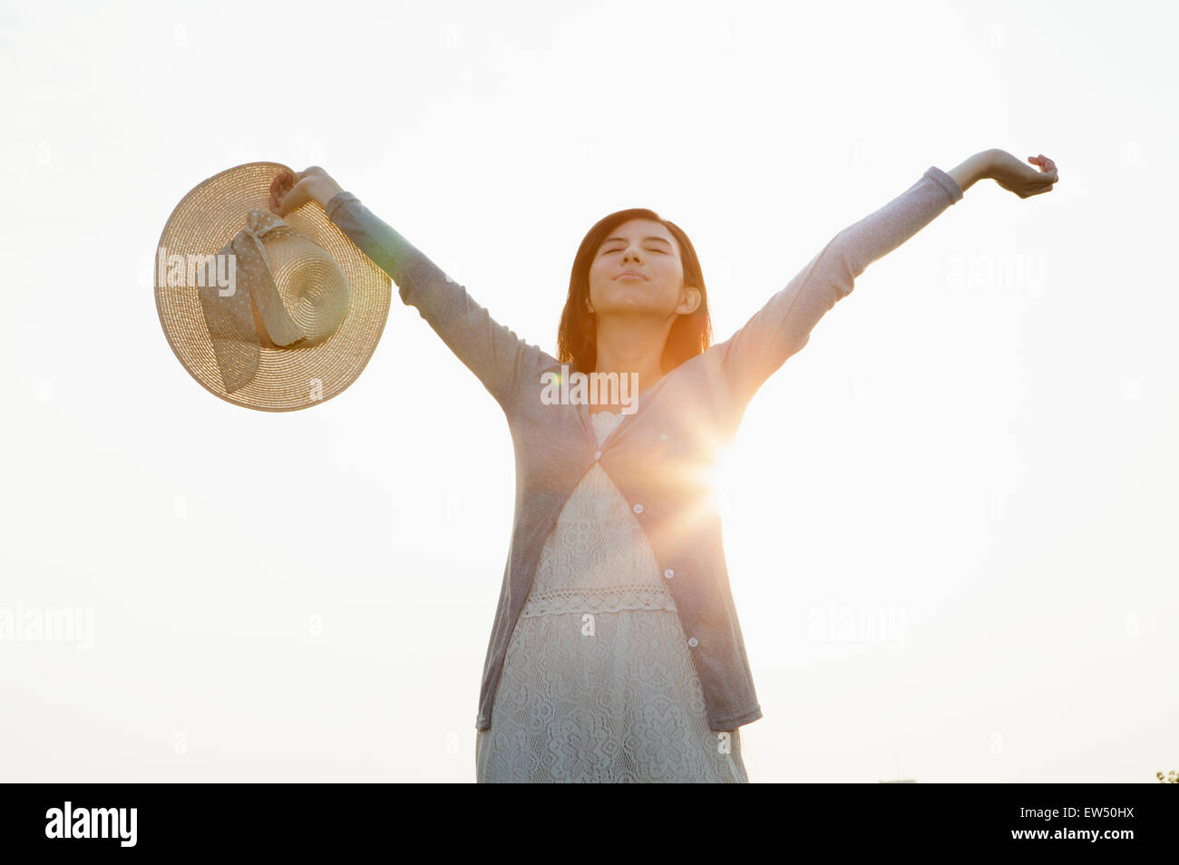 Young woman closing eyes with arms outstretched Stock Photo