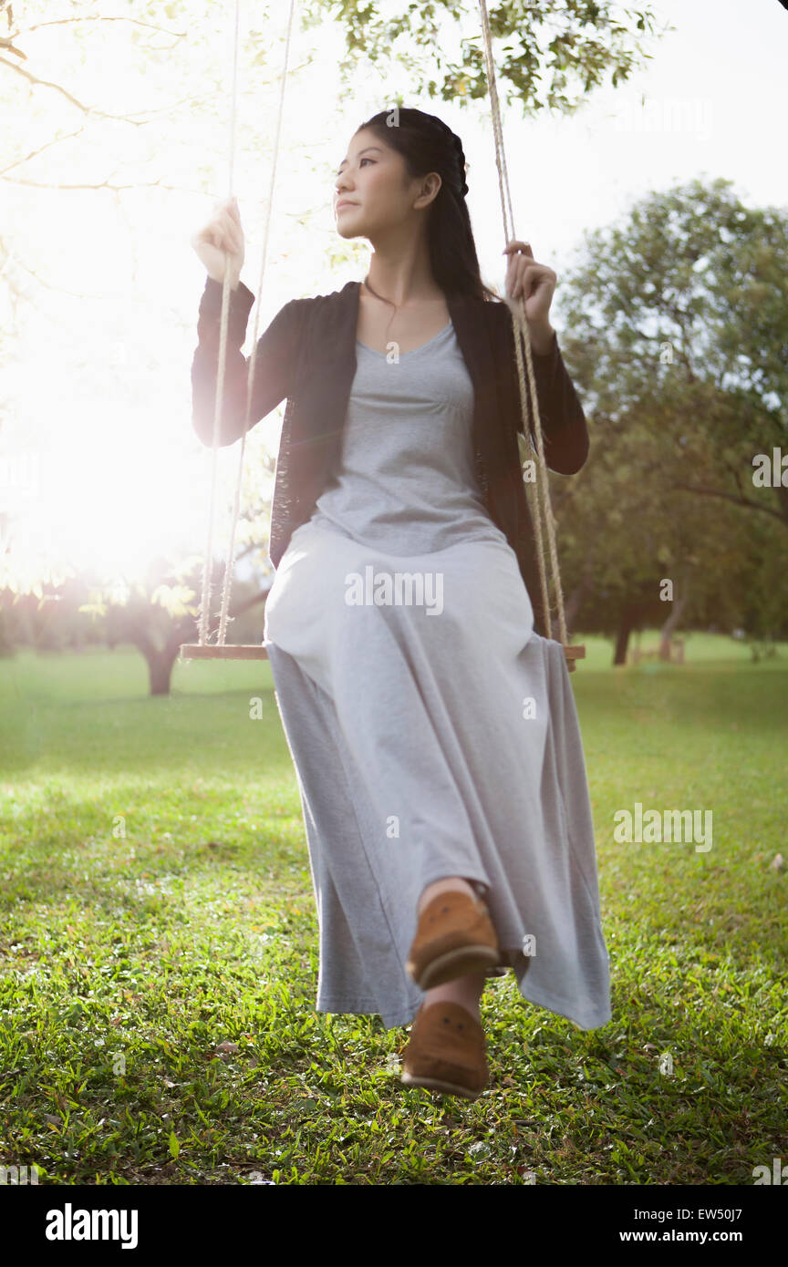 Young woman sitting on the swing and looking away Stock Photo - Alamy