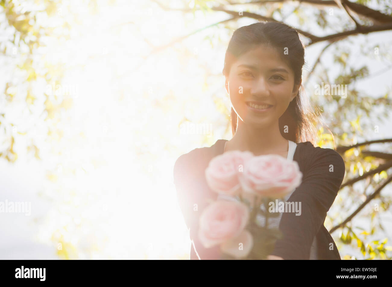 Young woman holding a bunch of flowers and smiling at the camera Stock ...
