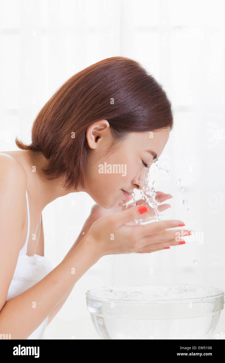 Young woman washing face with eyes closed Stock Photo