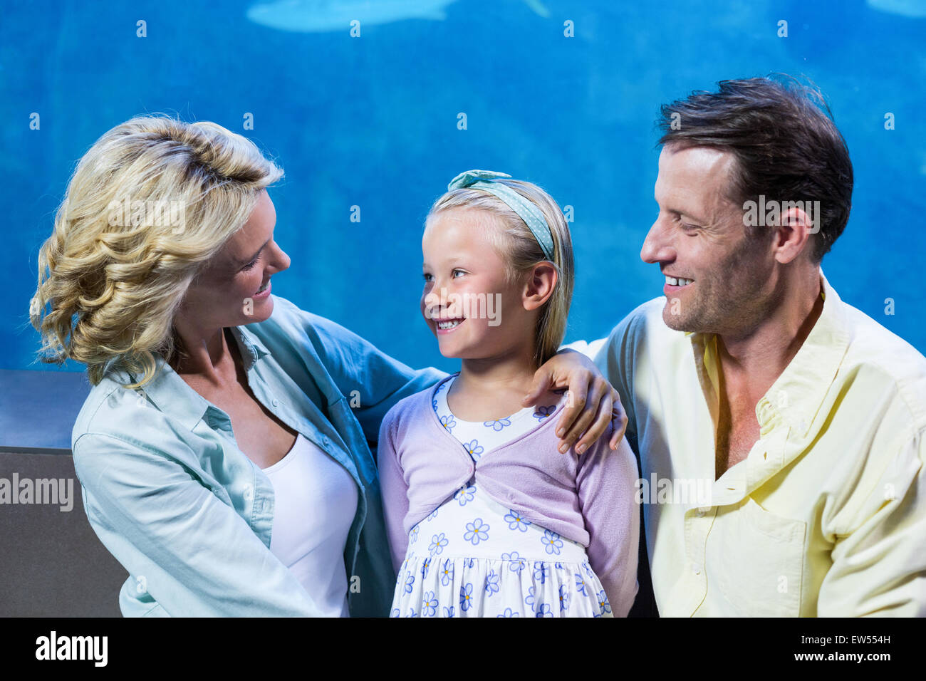 Happy family standing beside the fish tank Stock Photo
