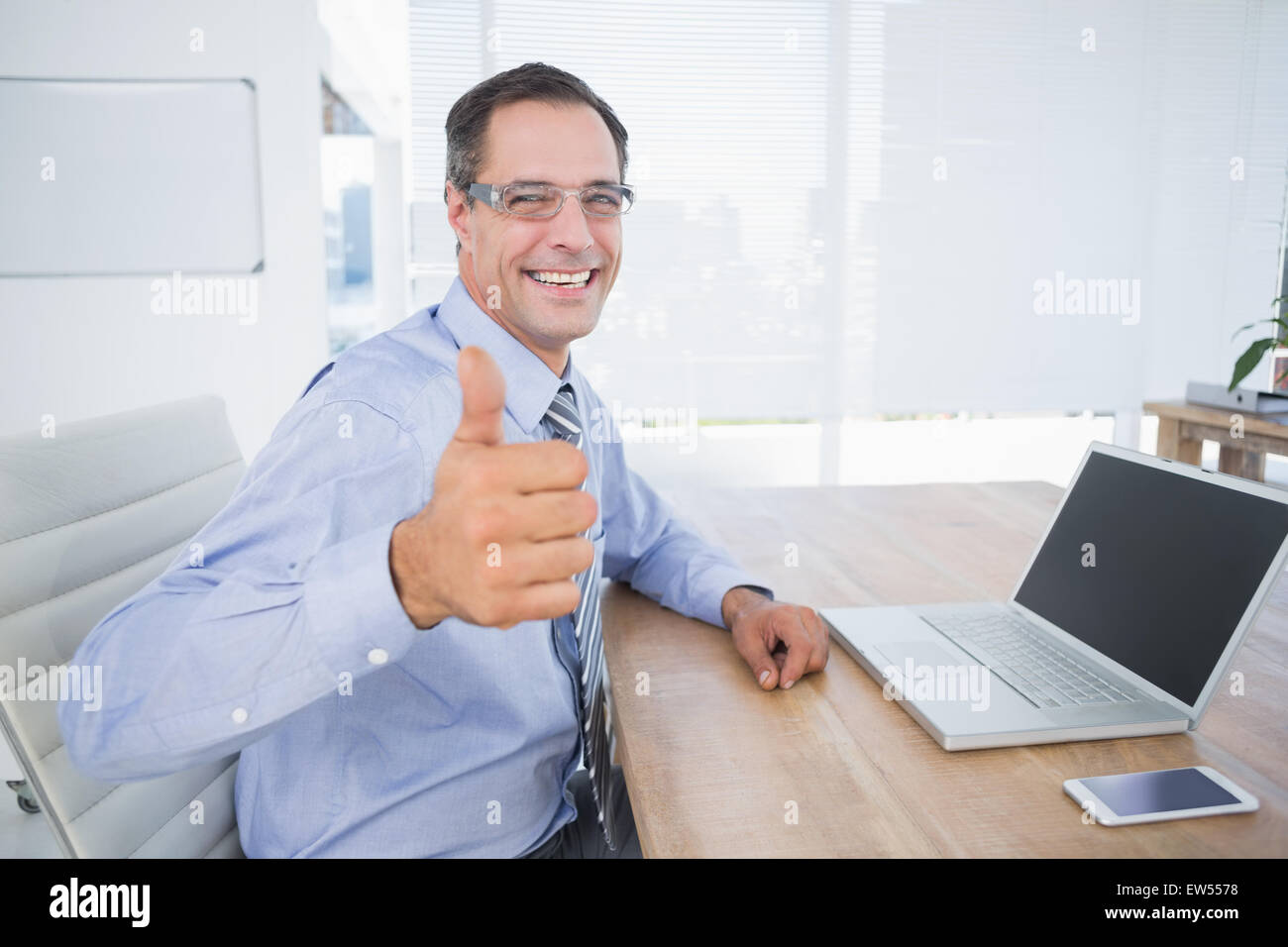 Businessman smiling at camera with thumbs up Stock Photo - Alamy