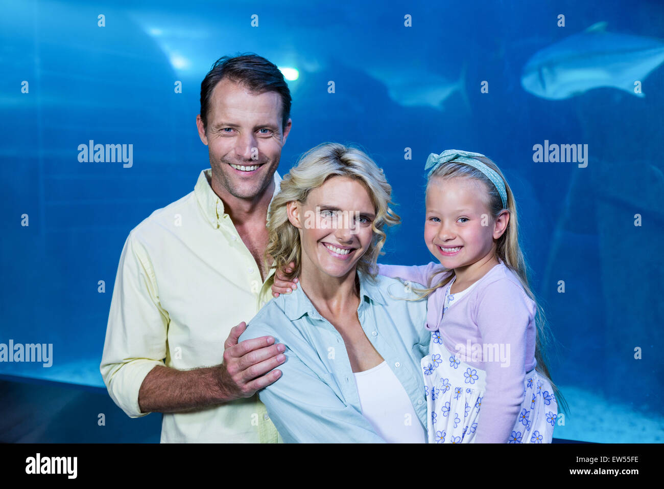 Happy family looking at camera beside the fish tank Stock Photo