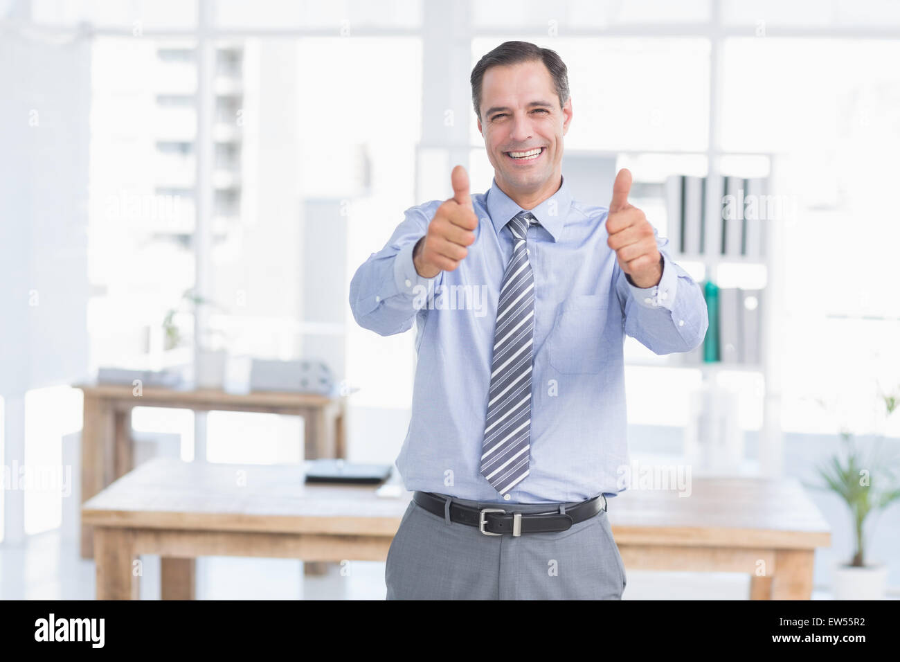 Businessman smiling at camera with thumbs up Stock Photo - Alamy