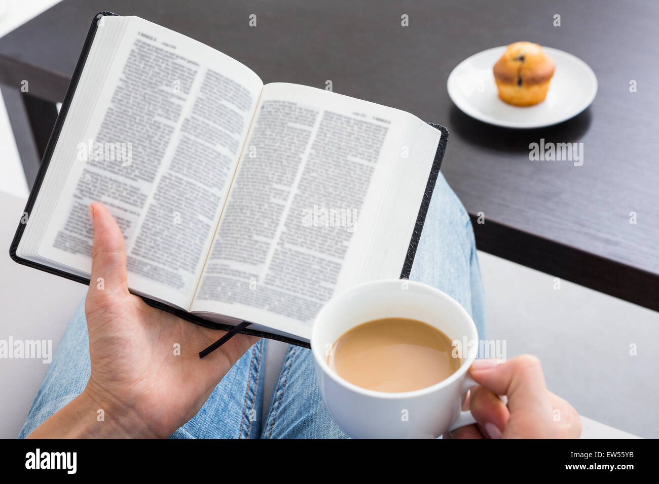 Woman reading a book and holding cup of coffee Stock Photo