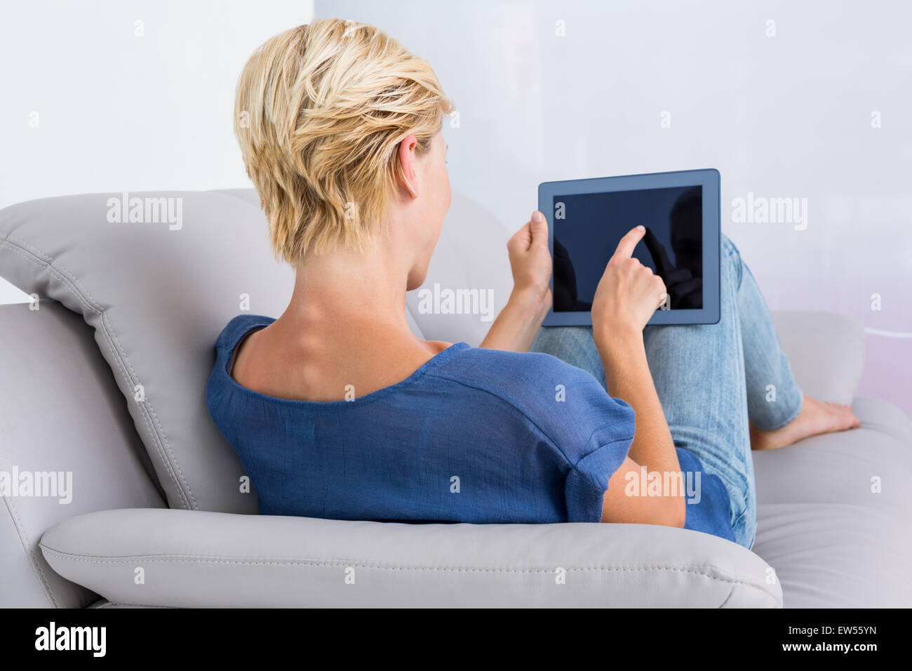 Blonde woman using her tablet on the couch Stock Photo