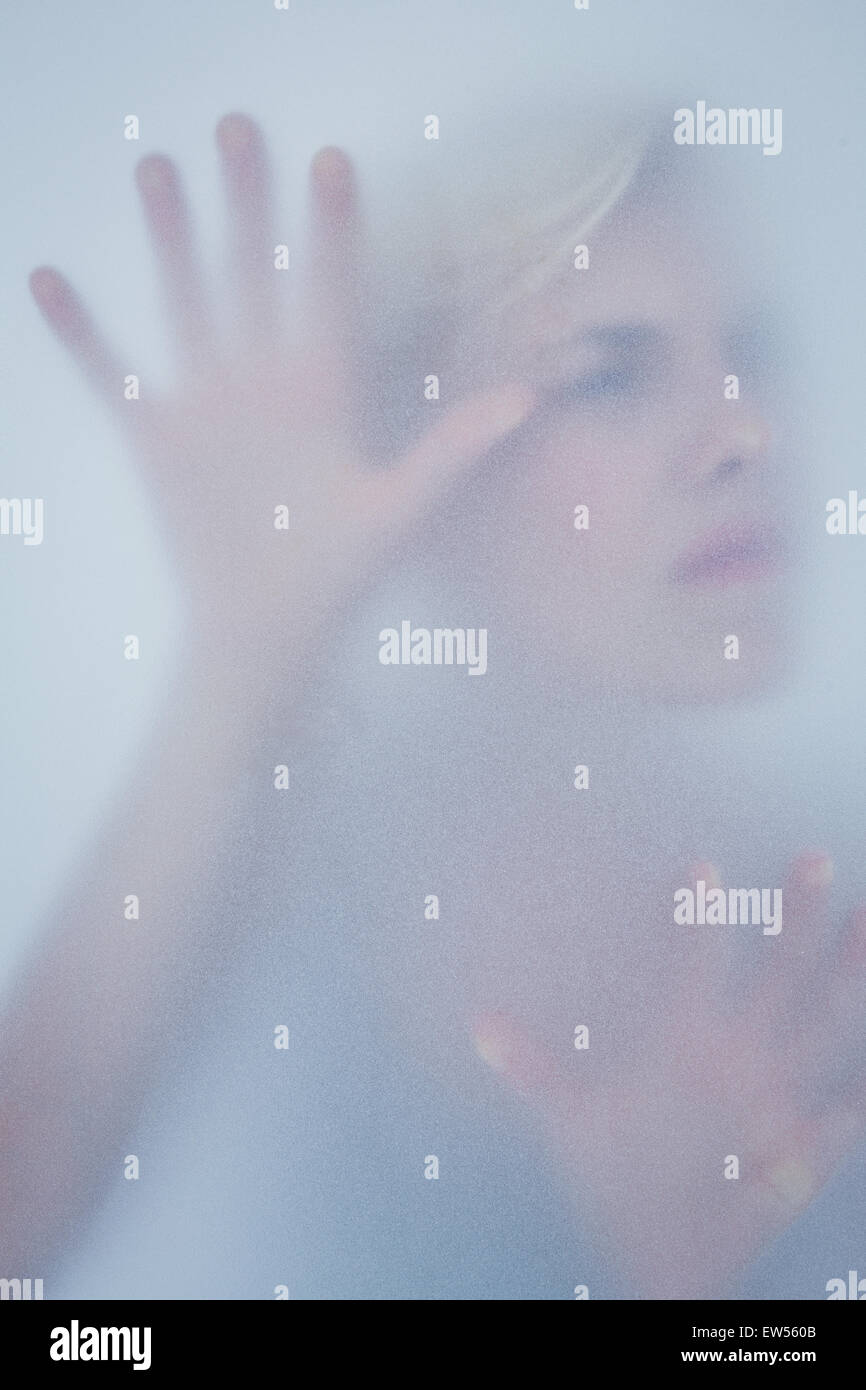 Blonde woman touching frosted glass Stock Photo