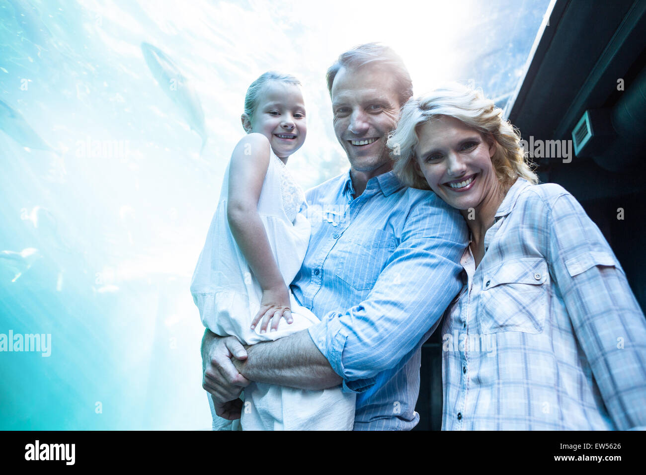 Happy family looking at camera behind a fish tank Stock Photo