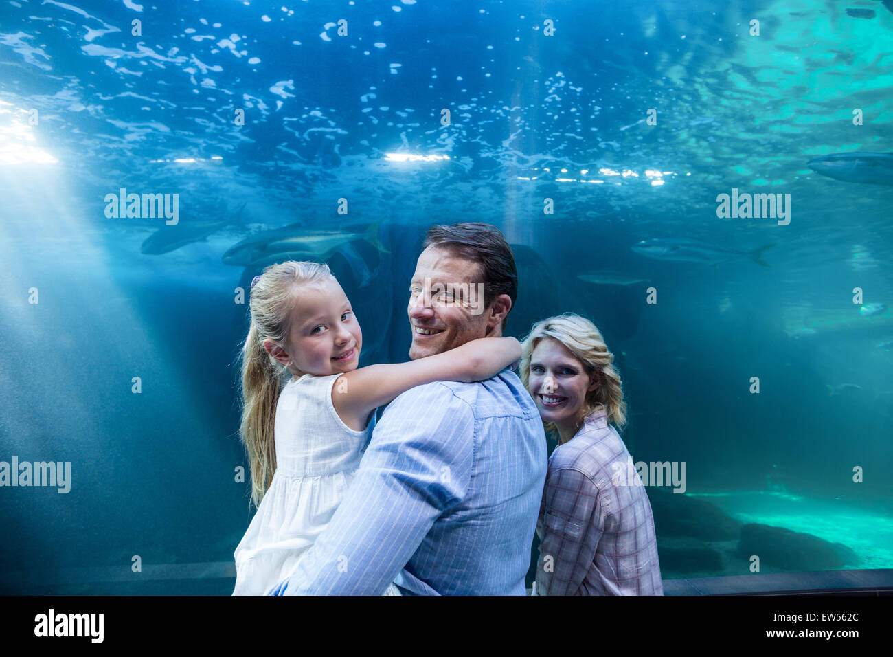 Happy family looking at camera behind a fish tank Stock Photo