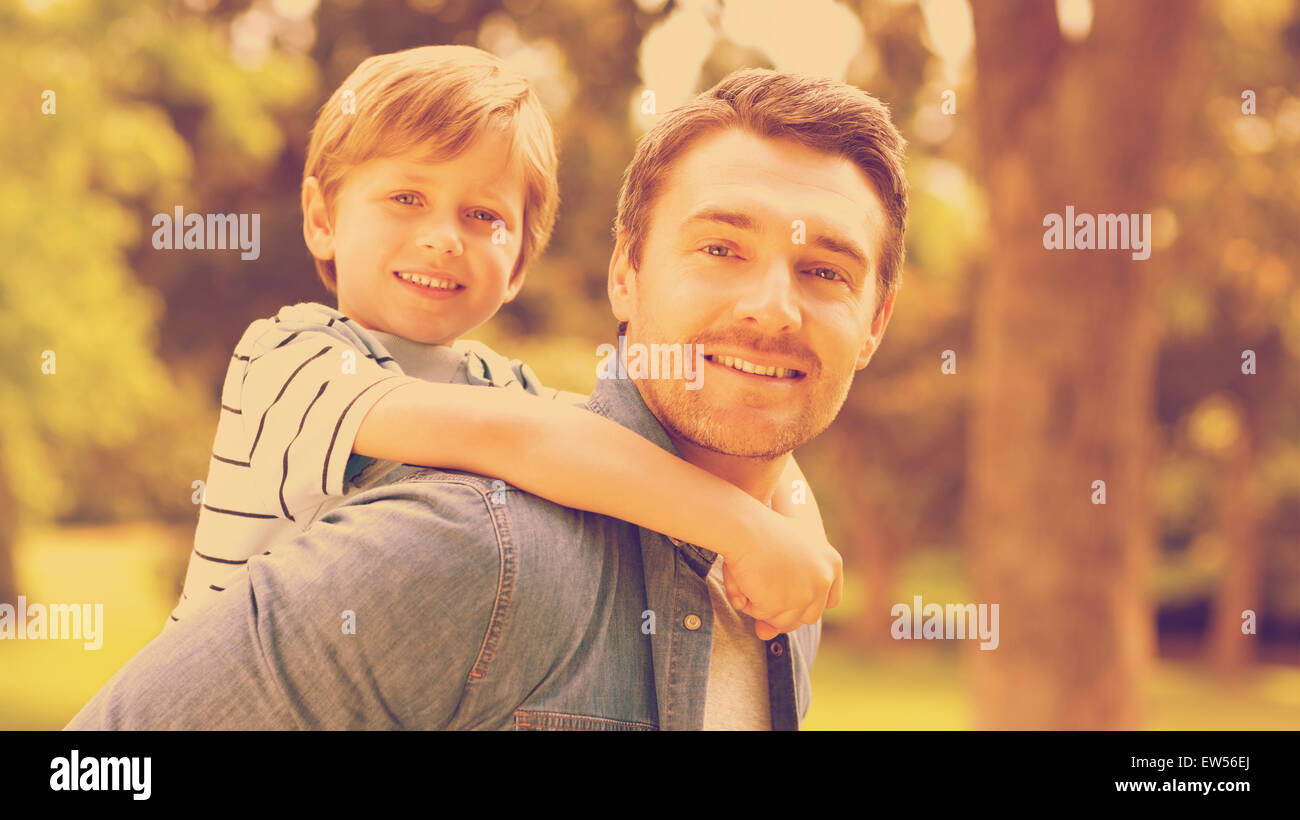 Father carrying young boy on back at park Stock Photo