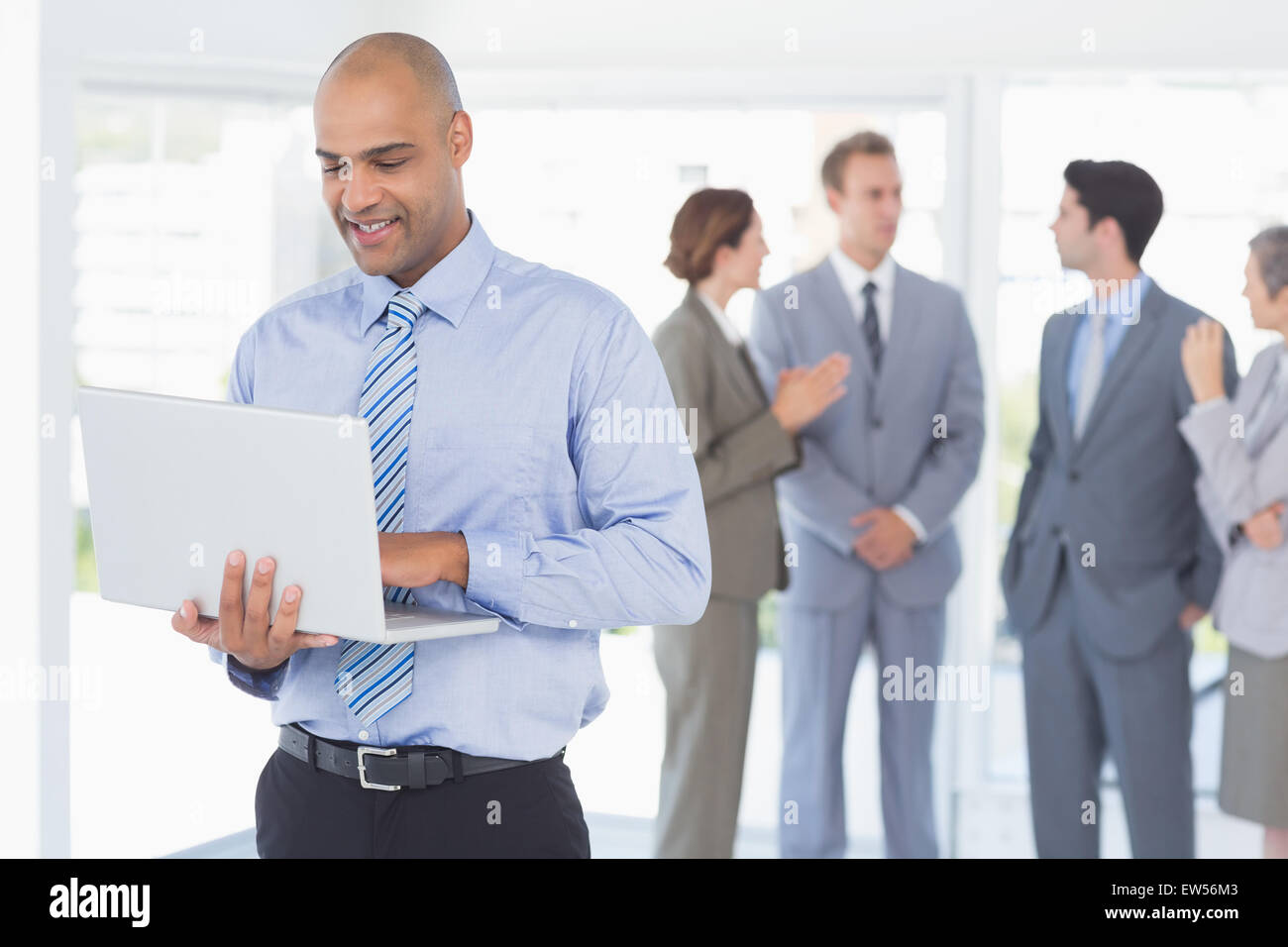 Businessman with his laptop and his colleagues behind Stock Photo
