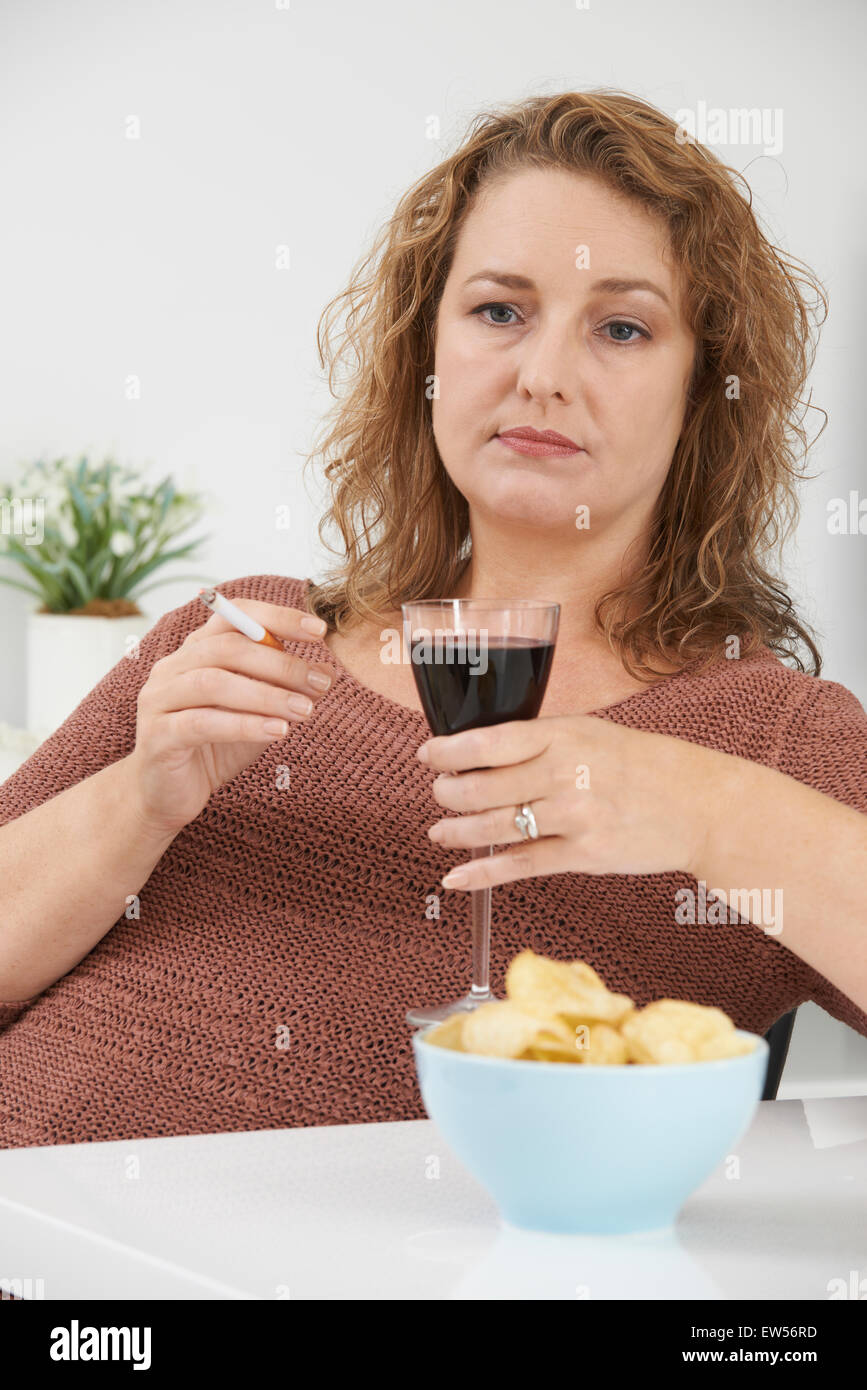 Woman Smoking Cigarette Whilst Drinking Wine And Eating Snacks Stock Photo