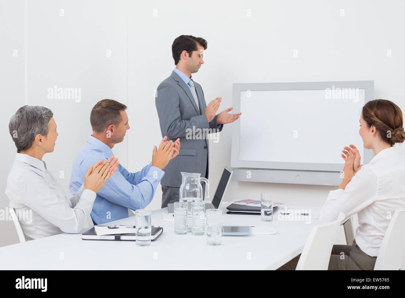 Business team applauding and looking at white screen Stock Photo