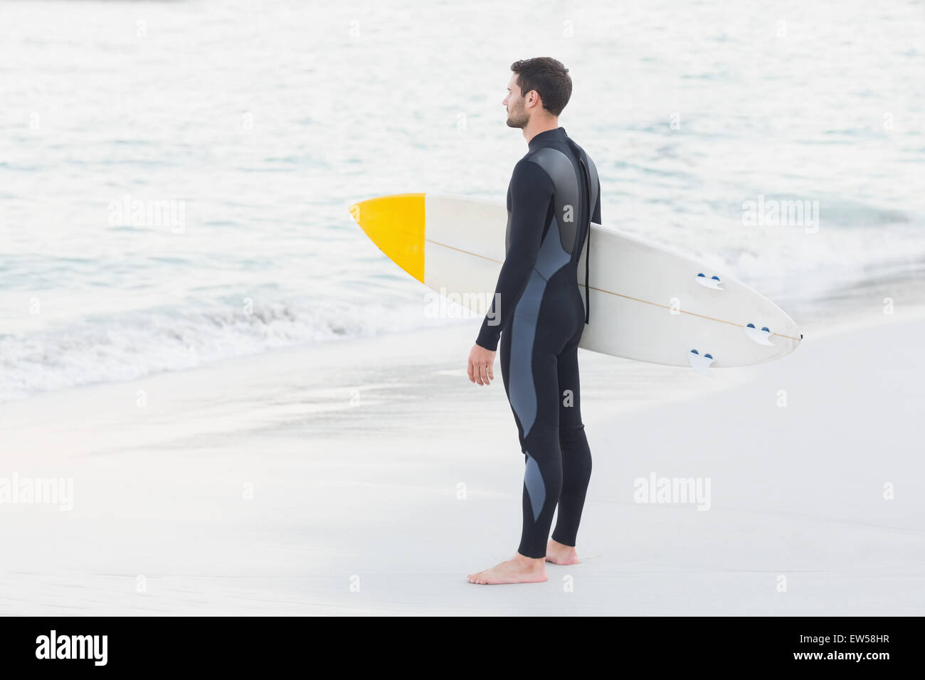 Man in wetsuit with a surfboard on a sunny day Stock Photo