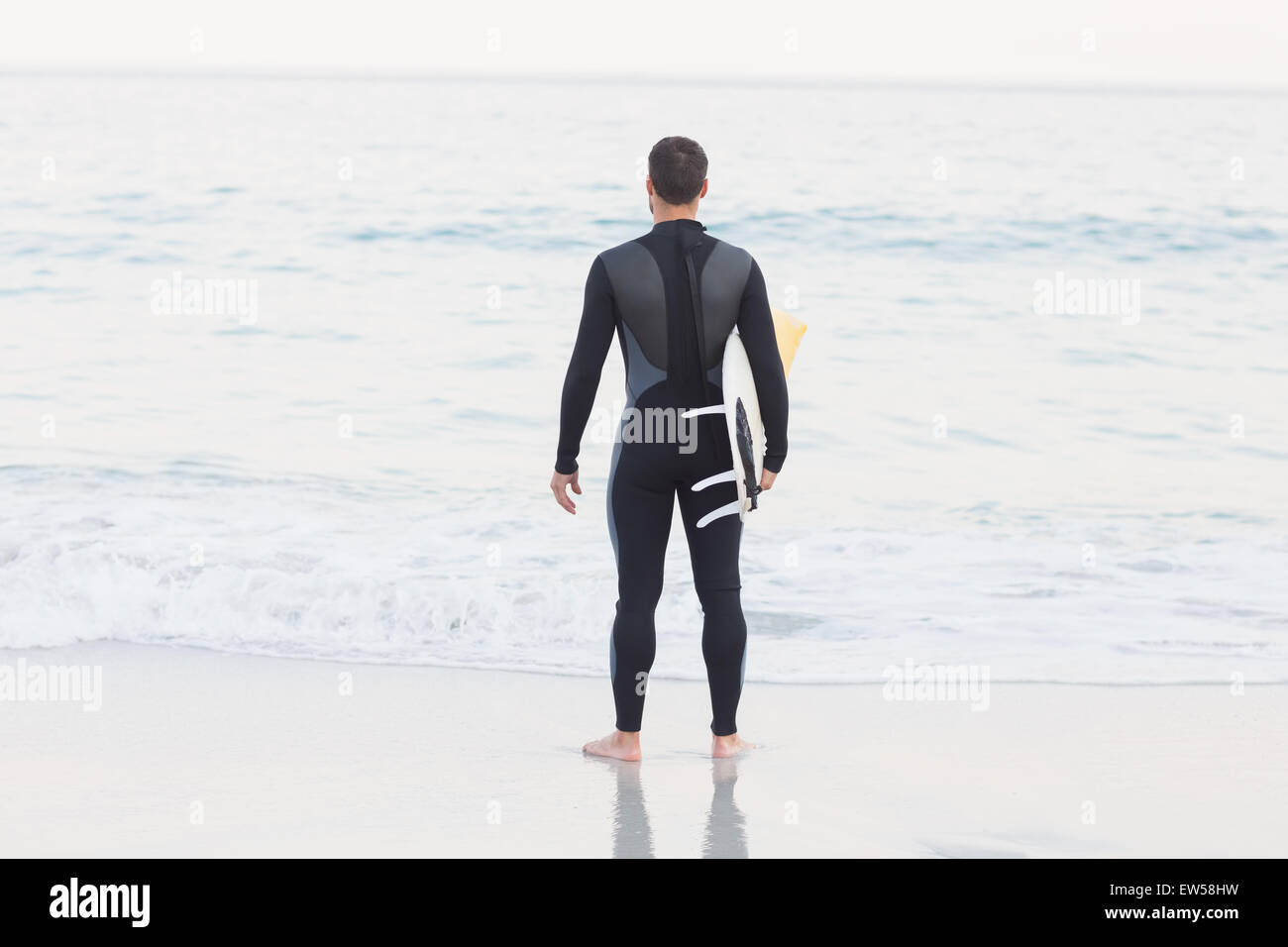 Man in wetsuit with a surfboard on a sunny day Stock Photo